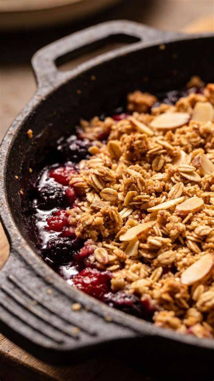 Closeup of a berry crisp with a scoop of yogurt in a white bowl.