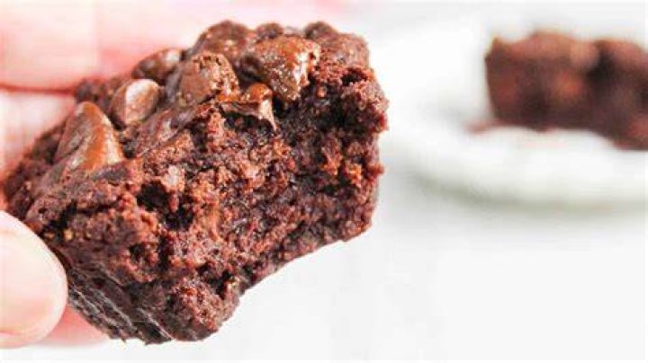 Half of a brownie bite topped with chocolate frosting and a raspberry.